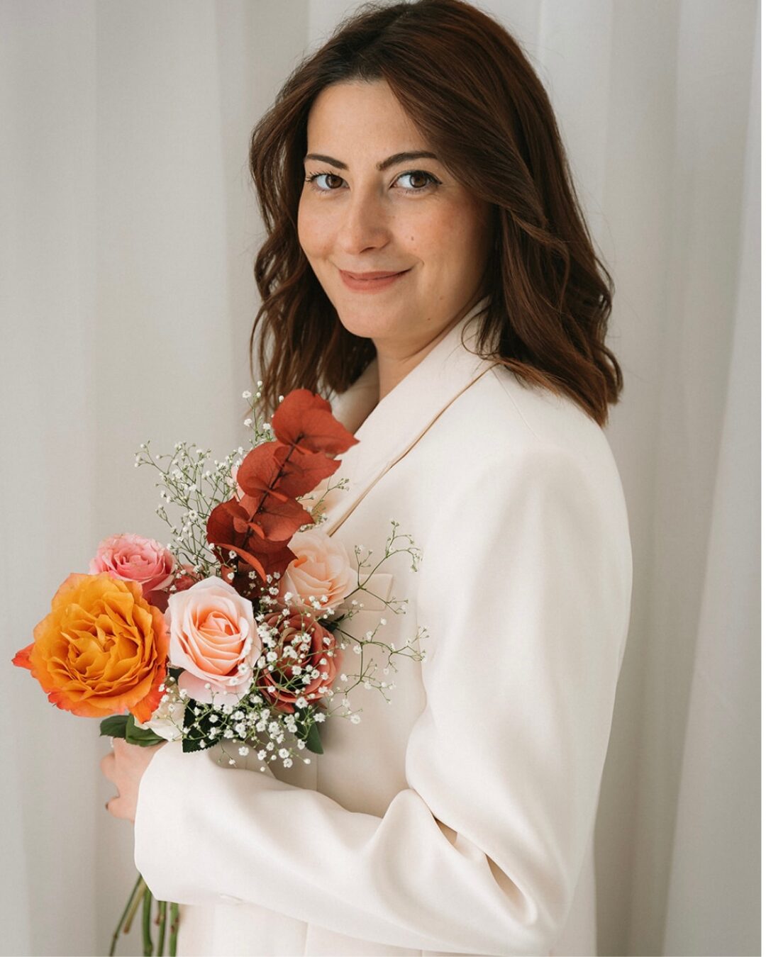 Mona von FLÓRAMI mit einem handgebundenen Blumenstrauß in Pastelltönen